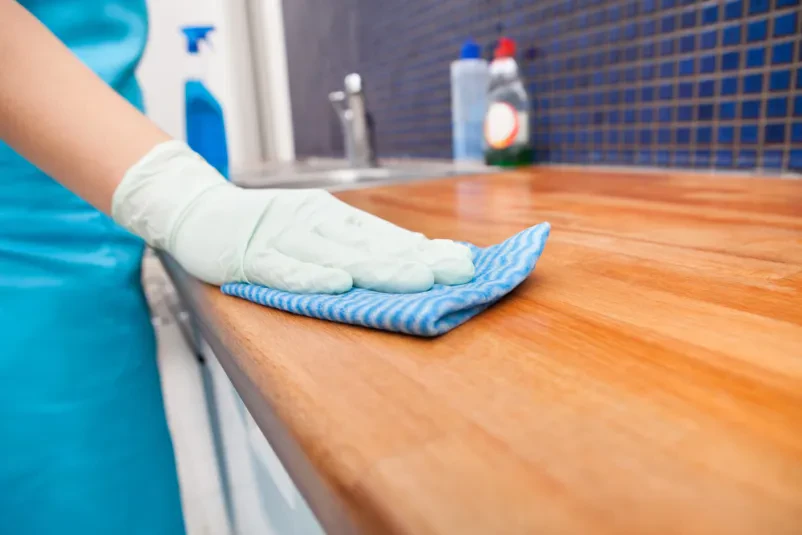 Professionelle Reinigungskraft reinigt Küchenarbeitsplatte mit blauem Mikrofasertuch