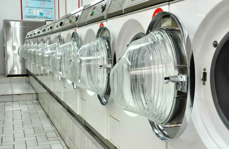 Moderne industrielle Waschmaschinen in einem professionellen Waschsalon mit großen Trommeln.