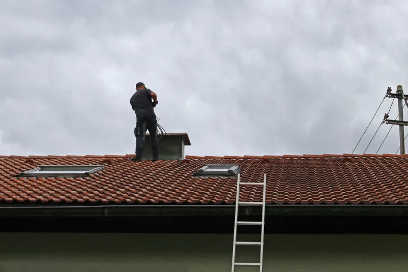 Dachdecker arbeitet auf einem Ziegeldach bei professioneller Dachsanierung.